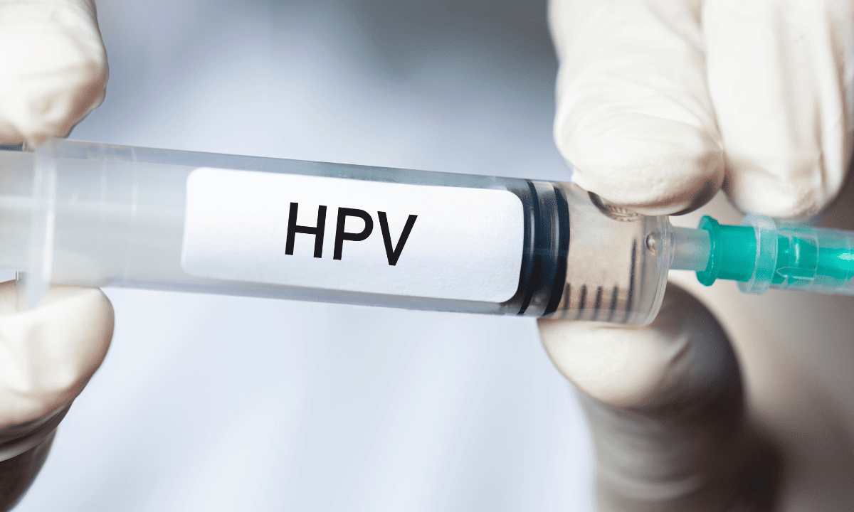 Close-up of gloved hands holding a syringe labeled 'HPV'