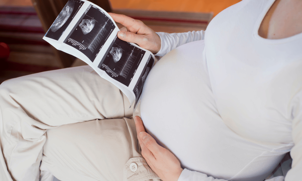 Image of pregnant woman holding ultrasound scan photos