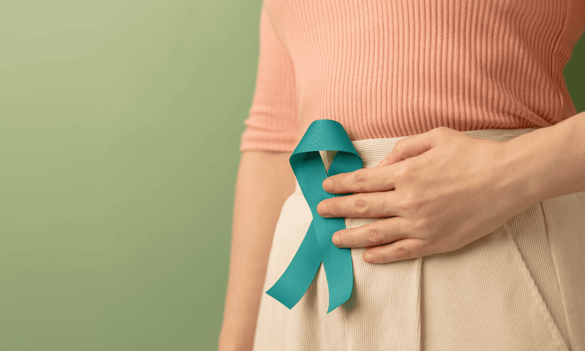 Close-up of a woman holding a teal cervical cancer awareness ribbon