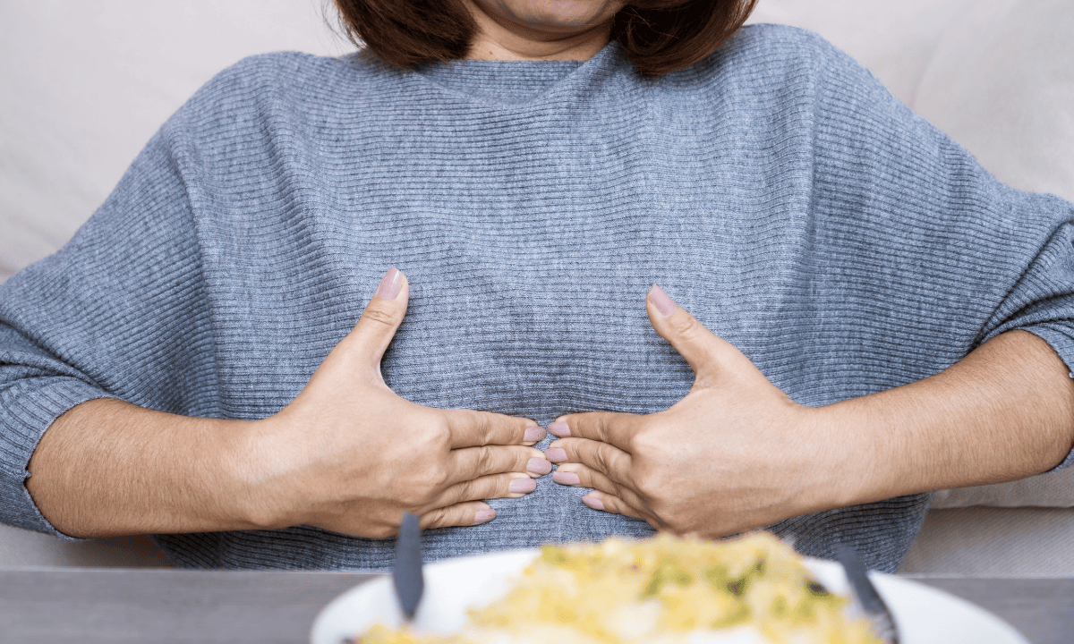 Image of a woman pressing slightly the upper central part of her abdomen