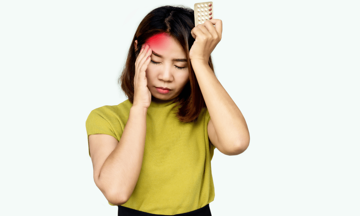 woman with a headache holding birth control pills