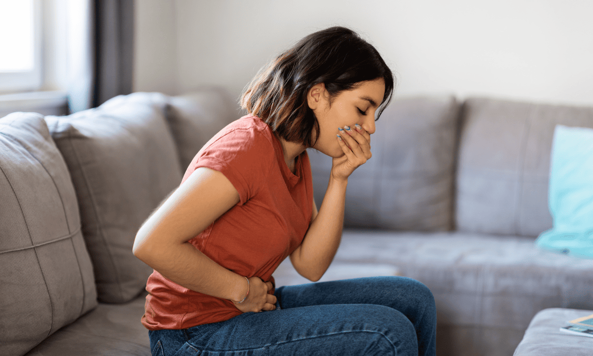 Woman holding her abdomen in discomfort due to stomach cramping or bloating. 