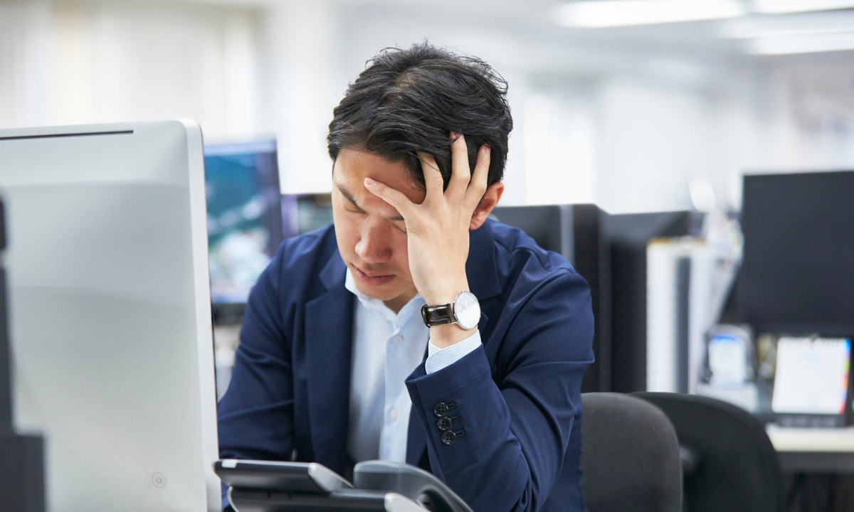 A man looking stressed and anxious, holding his head in his hands