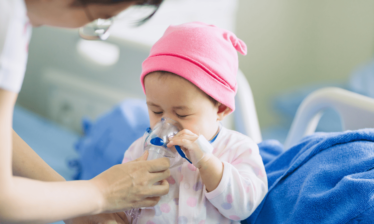 A toddler receiving paediatric asthma treatment using a nebulizer mask in a clinical setting