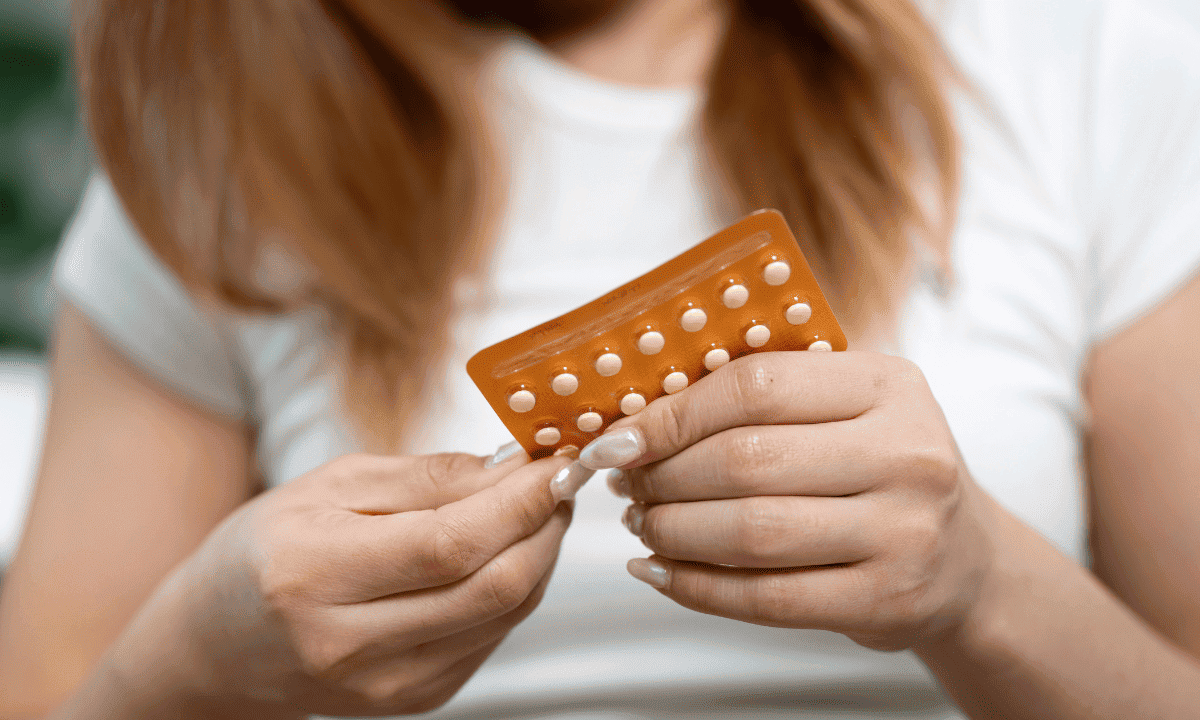 A person holding a blister pack of birth control pills in their hands.