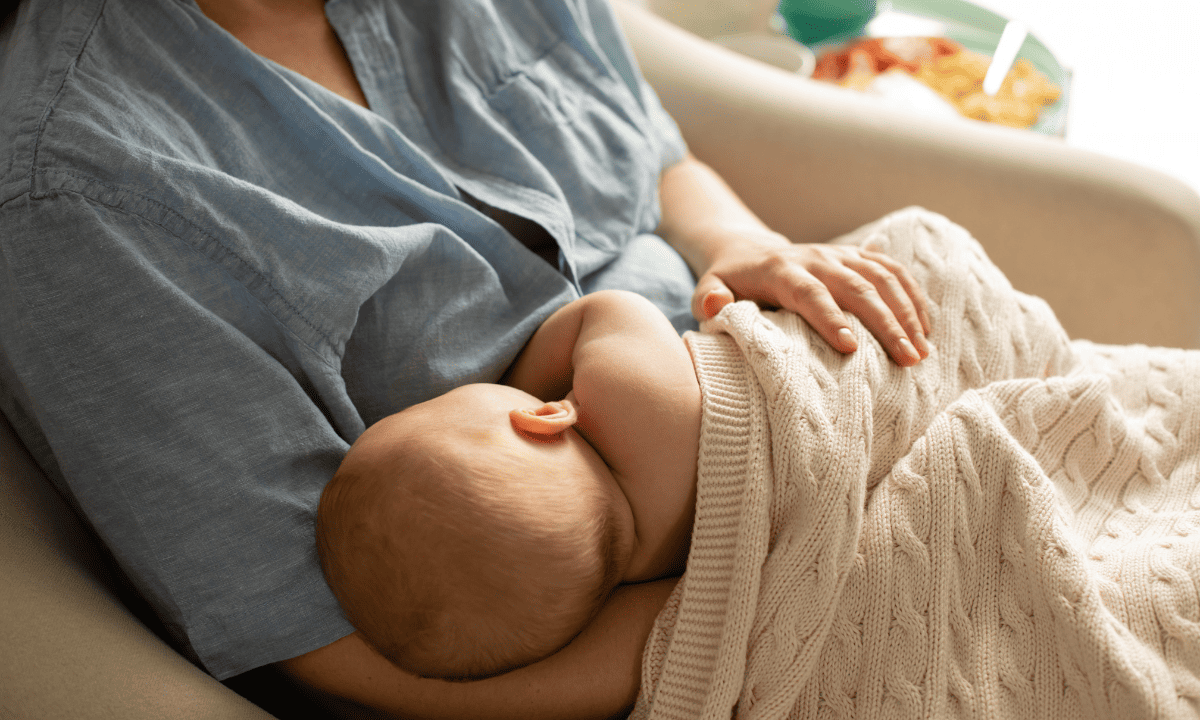 A mother breastfeeding her baby while sitting comfortably on a couch