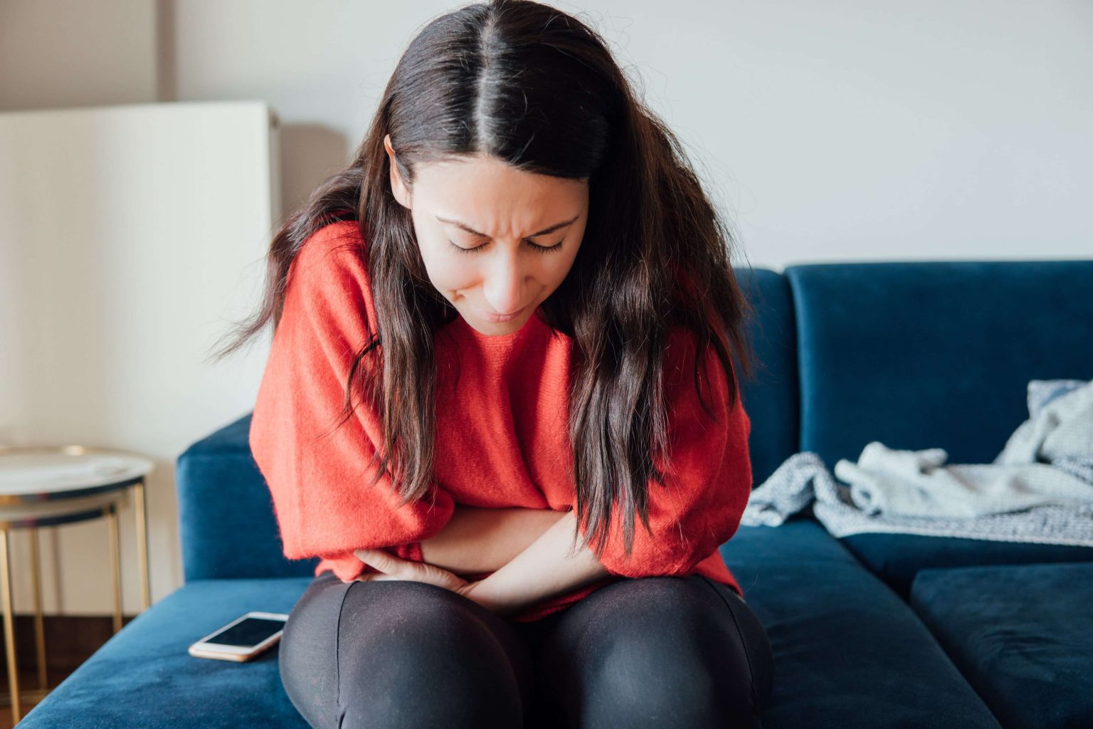 woman holding stomach in pain ovarian cyst symptoms and diagnosis