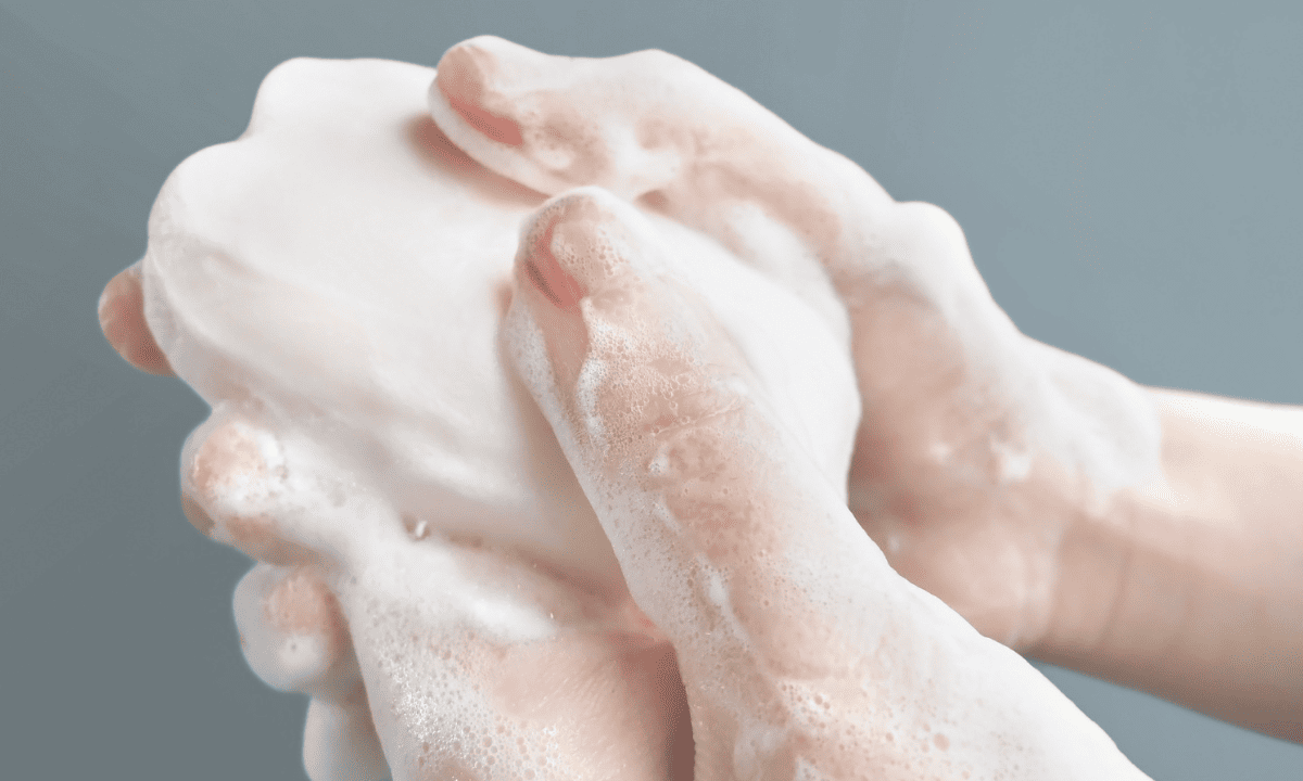 Close-up of hands being thoroughly washed with a bar of soap, creating thick white lather.