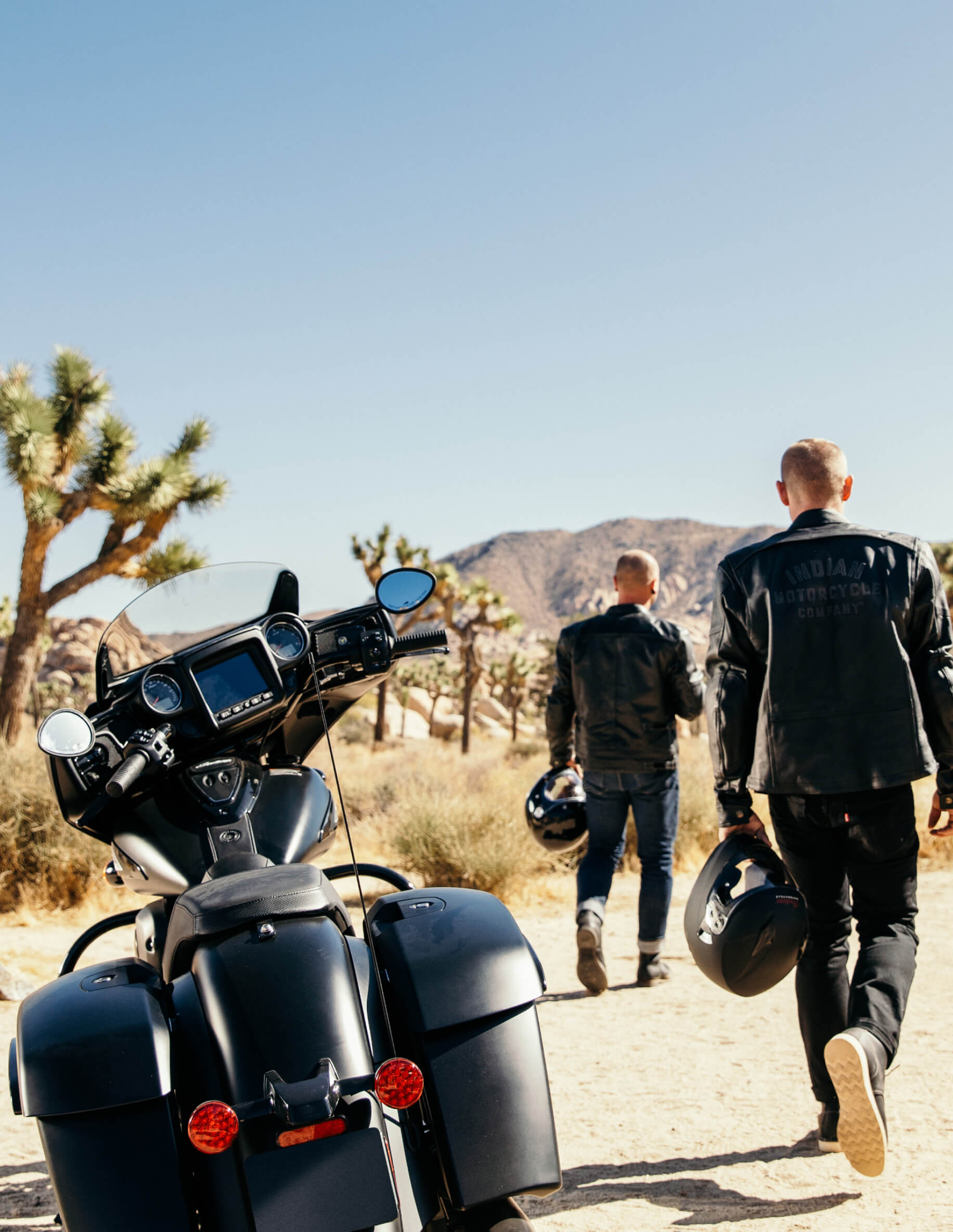 Two people in front of motorcycle in a desert