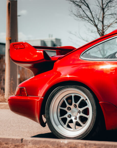 Close-up image of a red Porsche's rear tire and bumper