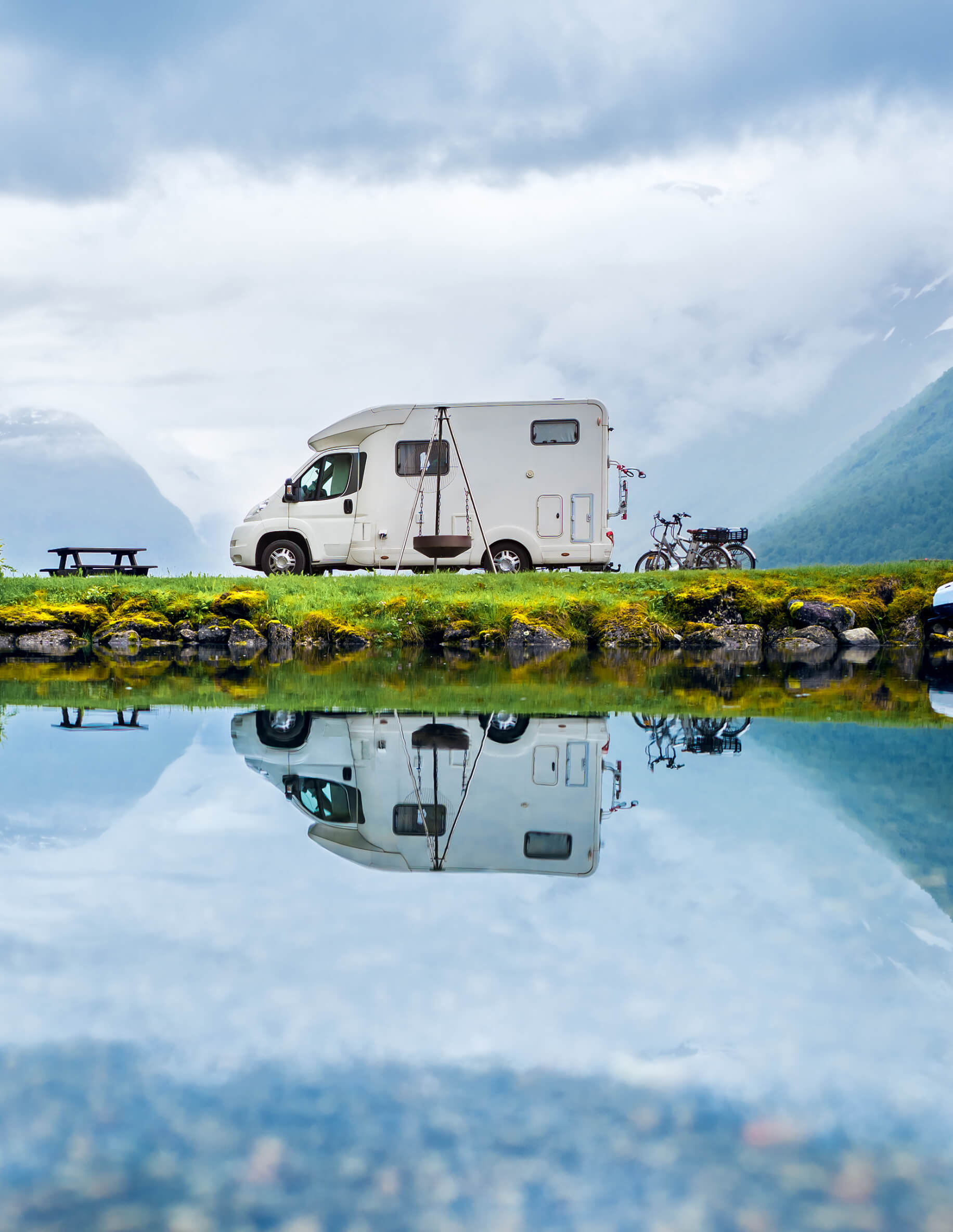 RV parked at the water with mountains in the background