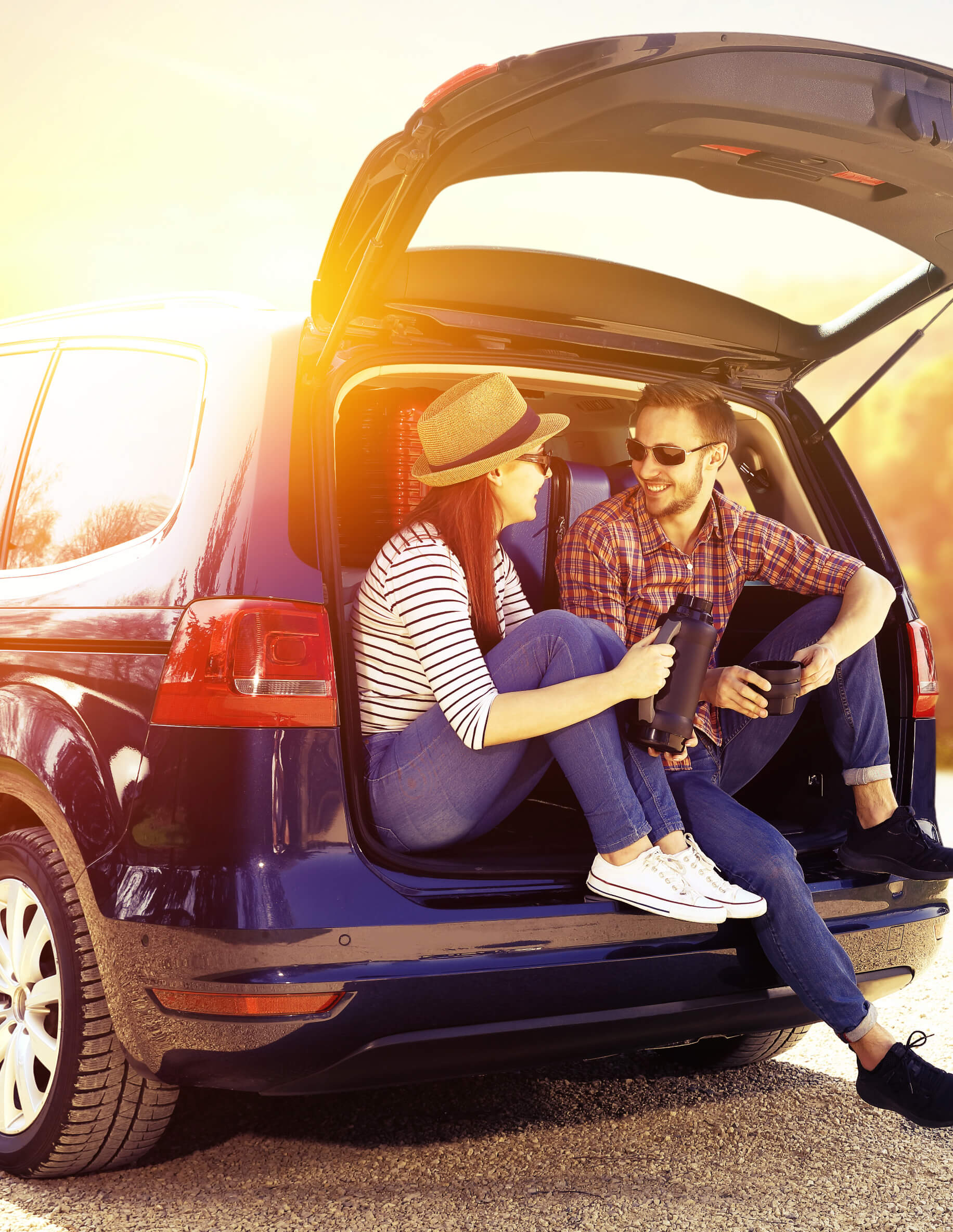 Couple drinking coffee at the back of their car