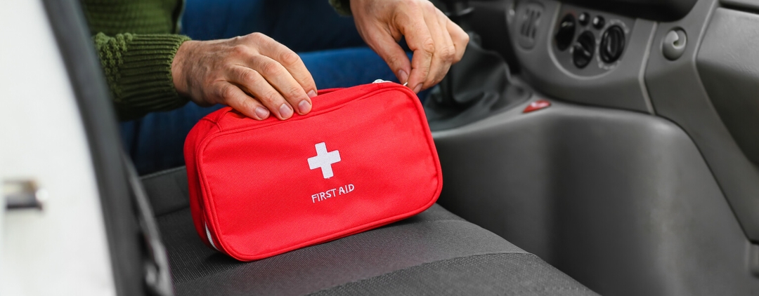 Two hands opening a red first aid kit