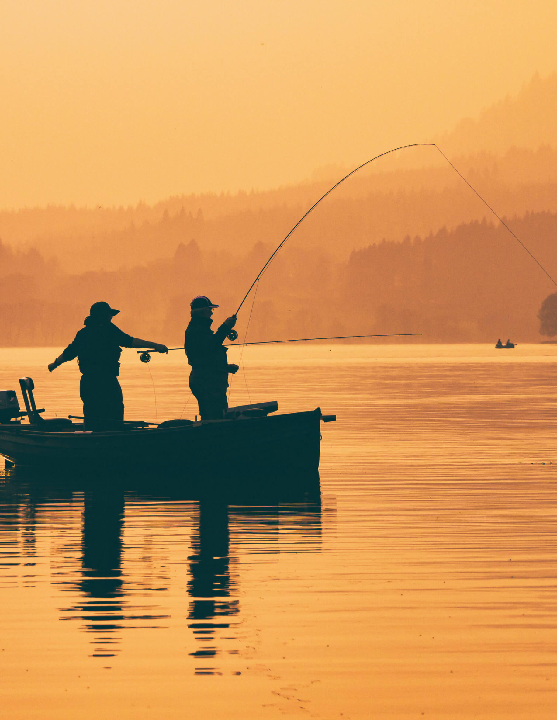 Two fisherman on a small boat with lines cast 