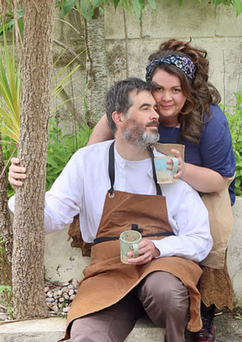 Makers in work aprons holding mugs they have made