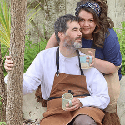 Makers in work aprons holding mugs they have made
