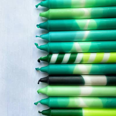 A selection of dip dyed candles in various shades of green.