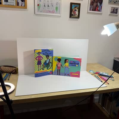 Set up of a photo shooting with two books set up next to each other to be photographed on a white backdrop surrounded by lights