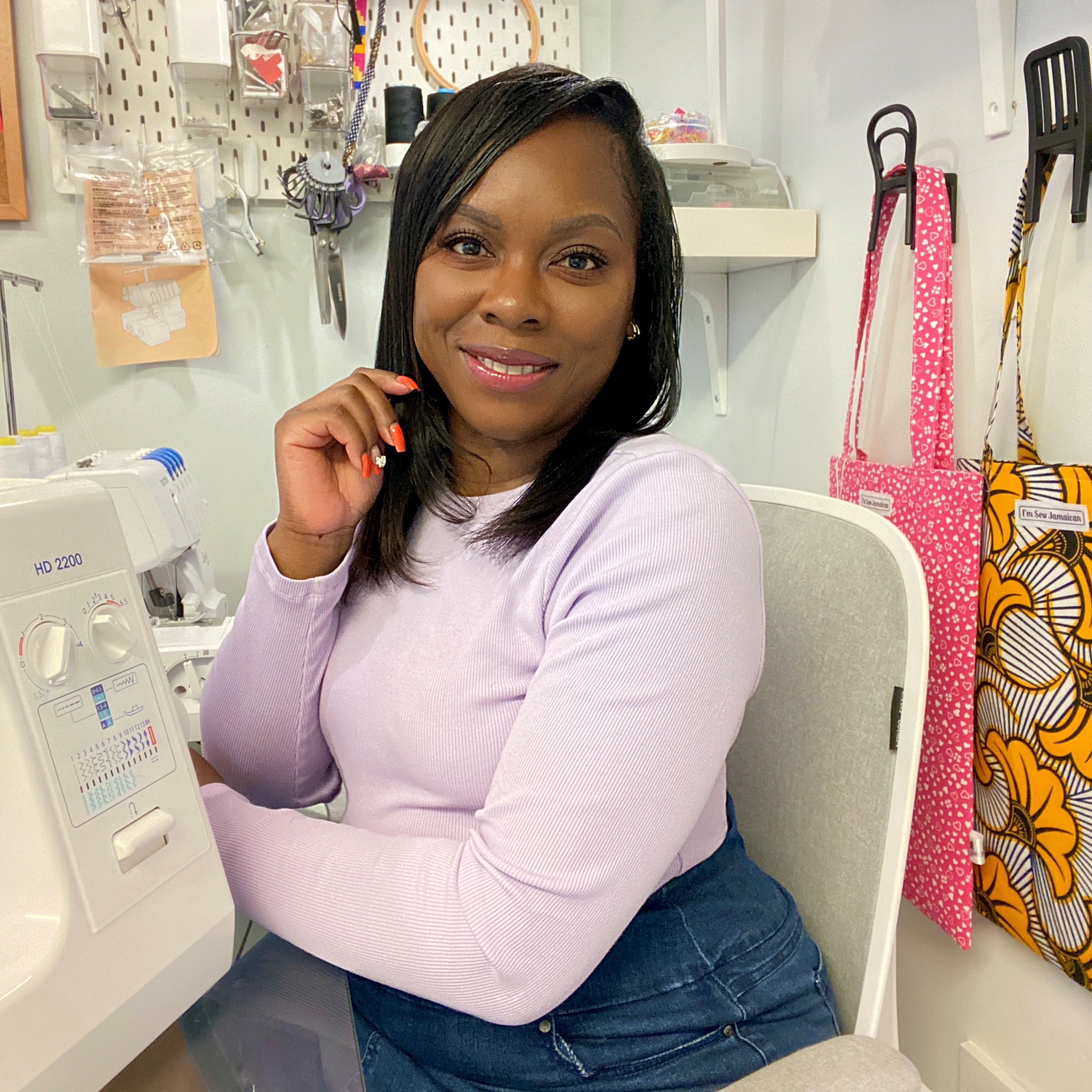 Black woman sitting beside sewing machine in craft studio
