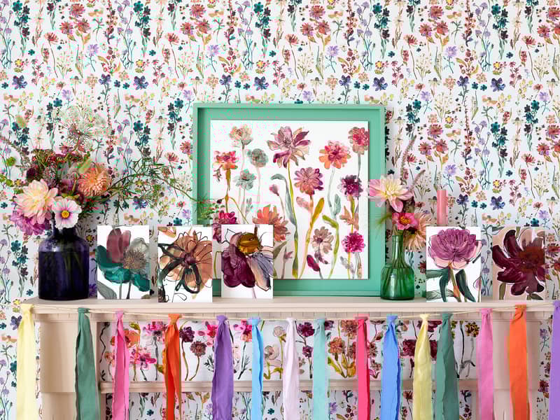 A mantelpiece with lots of floral Floradore cards. The cards are in front of a floral wallpaper and floral painting. Basically, floral-tastic maximalist stye!