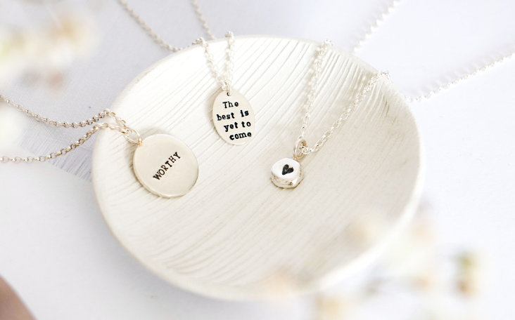 a textured white dish with three silver necklaces