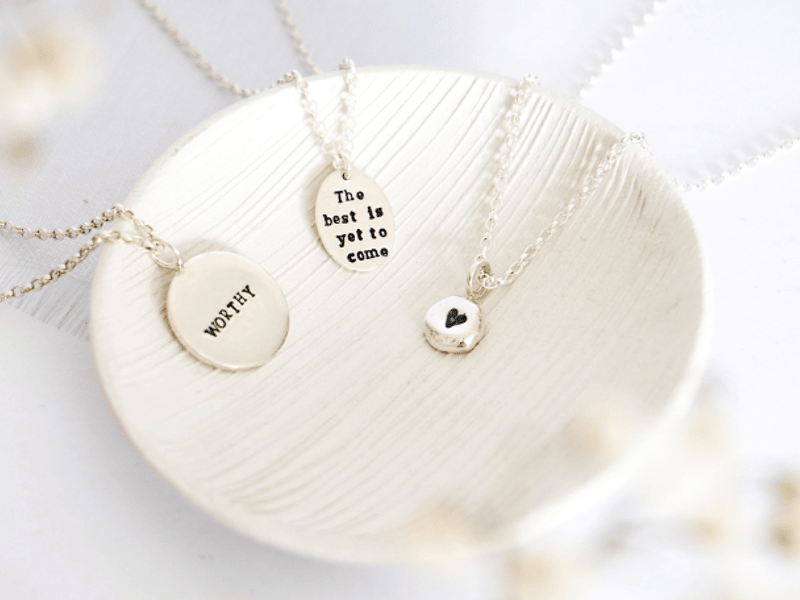 a textured white dish with three silver necklaces