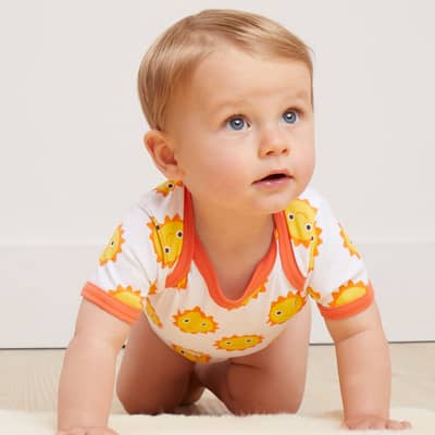 A baby crawling wearing a Toby Tiger Organic Gift Set - Sun Cloud Print