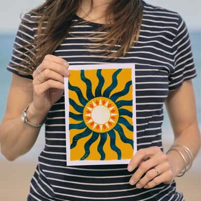 A woman holding a yellow and blue sunshine print
