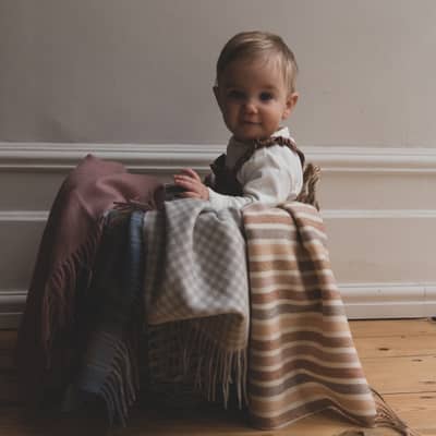 cute baby sat in basket with blankets