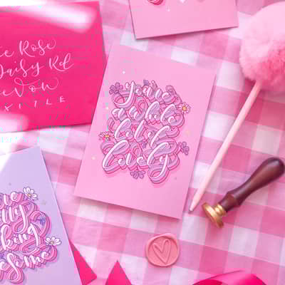 Colourful calligraphy greeting cards on a pink gingham background