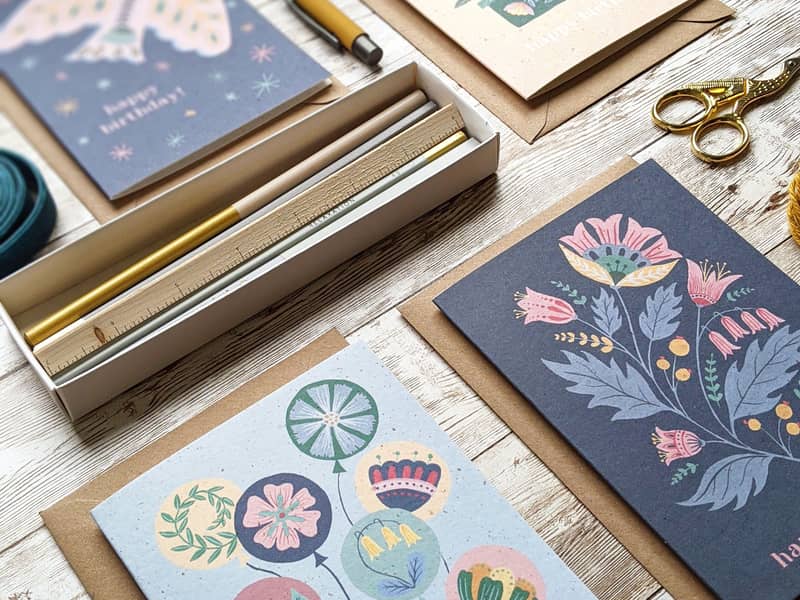 A selection of folk art birthday cards lying on a tabletop