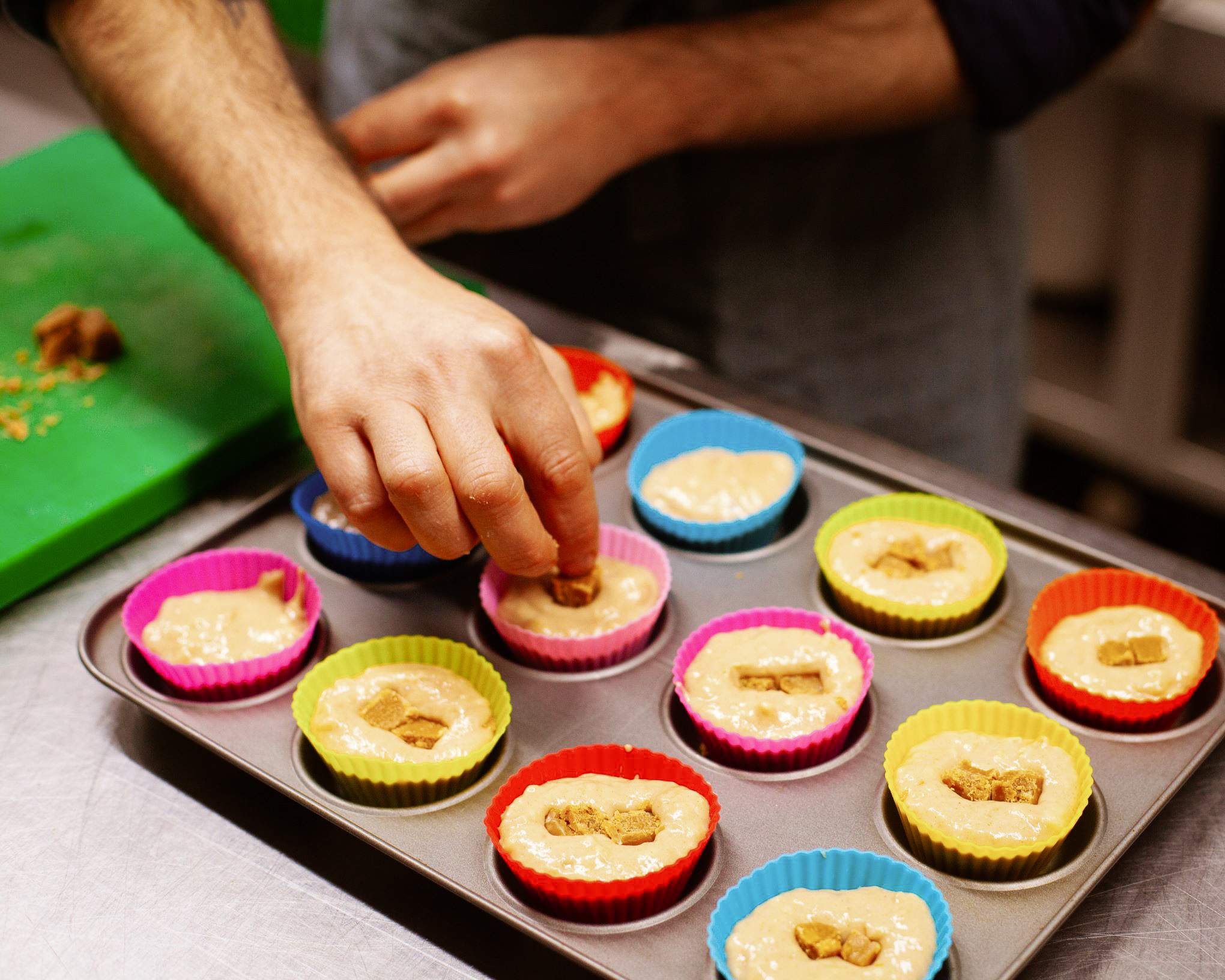 hand picking up a mix and rise strawberry fudge and vanilla plant-based muffin