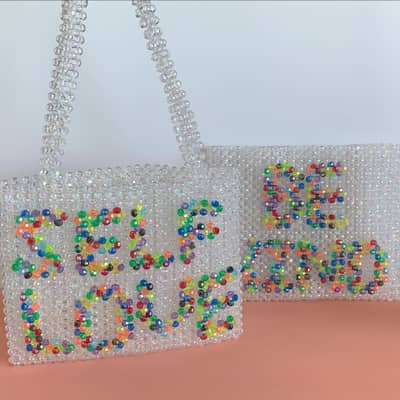 Iridescent beaded bags with rainbow words on the front, self love and be kind