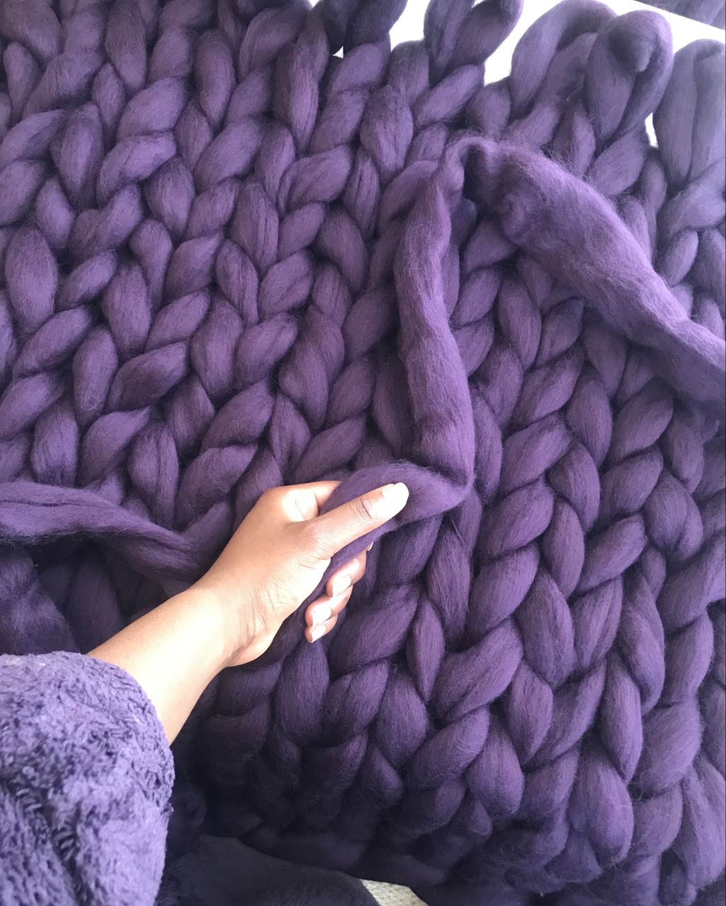 Nadine holding the end of the wool with half knitted blanket
