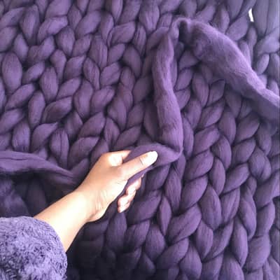Nadine holding the end of the wool with half knitted blanket