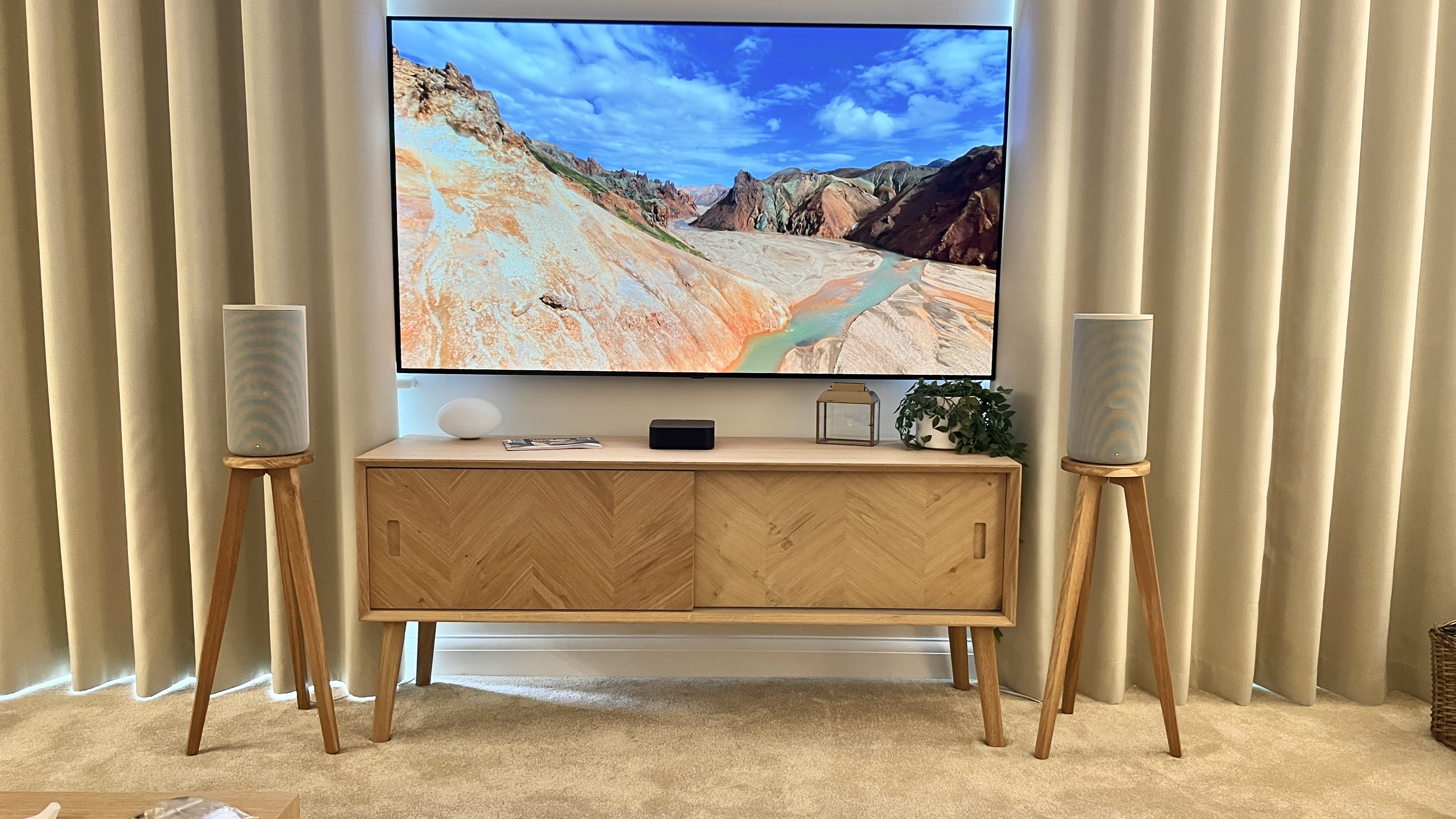 In situ shot of shaped topped solid oak tri leg speaker stands for HT-A9