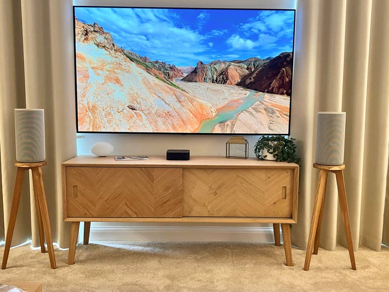 In situ shot of shaped topped solid oak tri leg speaker stands for HT-A9