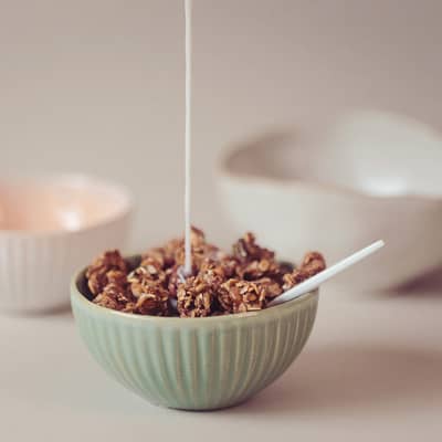 Granola in a bowl with milk being poured in