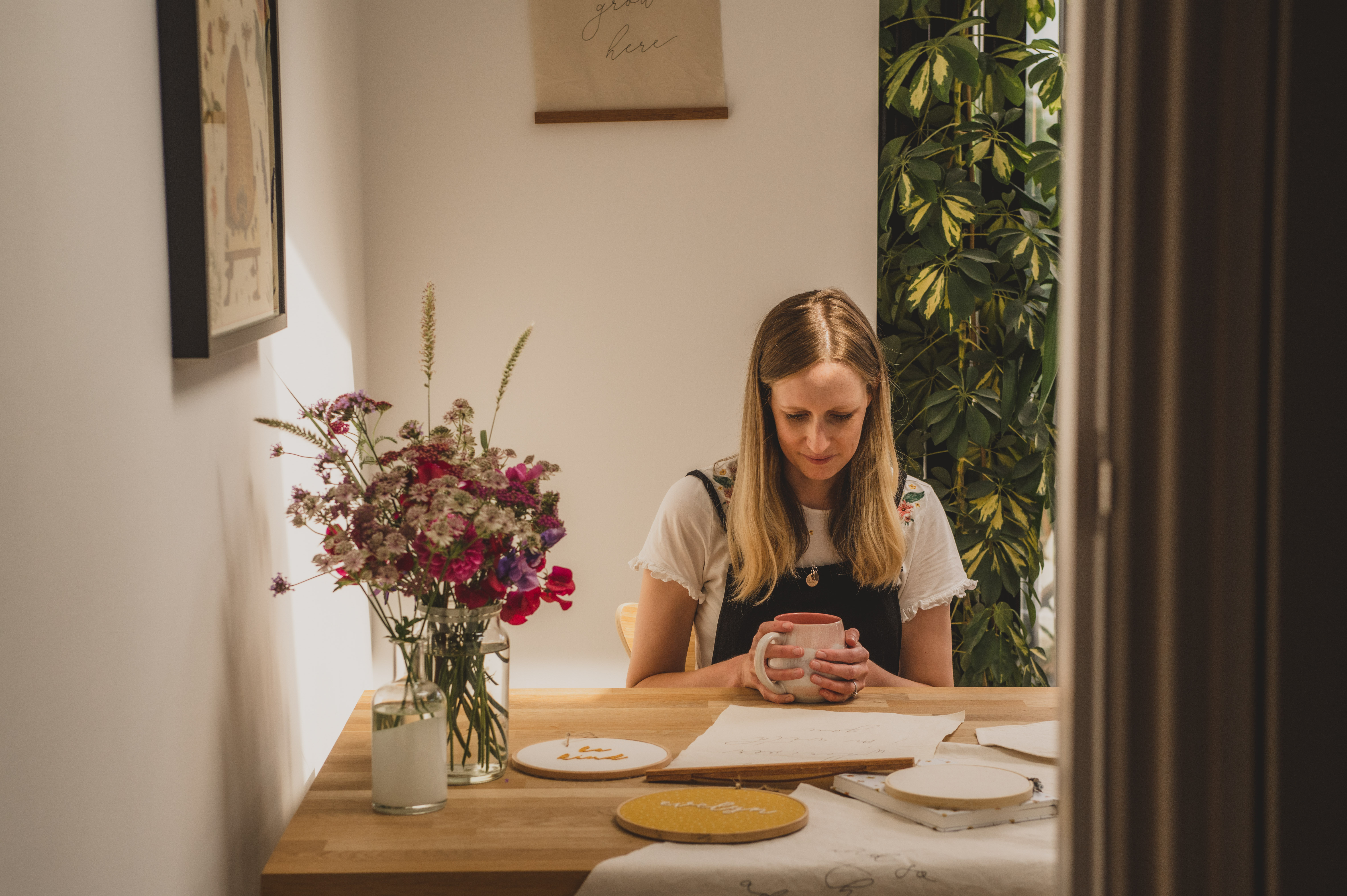Becky sitting at table with fabric banners and flowers and cup of tea