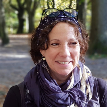 A photo of a woman's head and shoulders with a background of trees