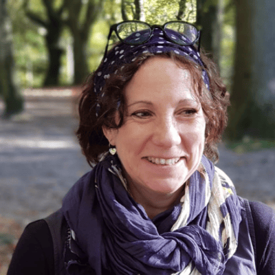 A photo of a woman's head and shoulders with a background of trees