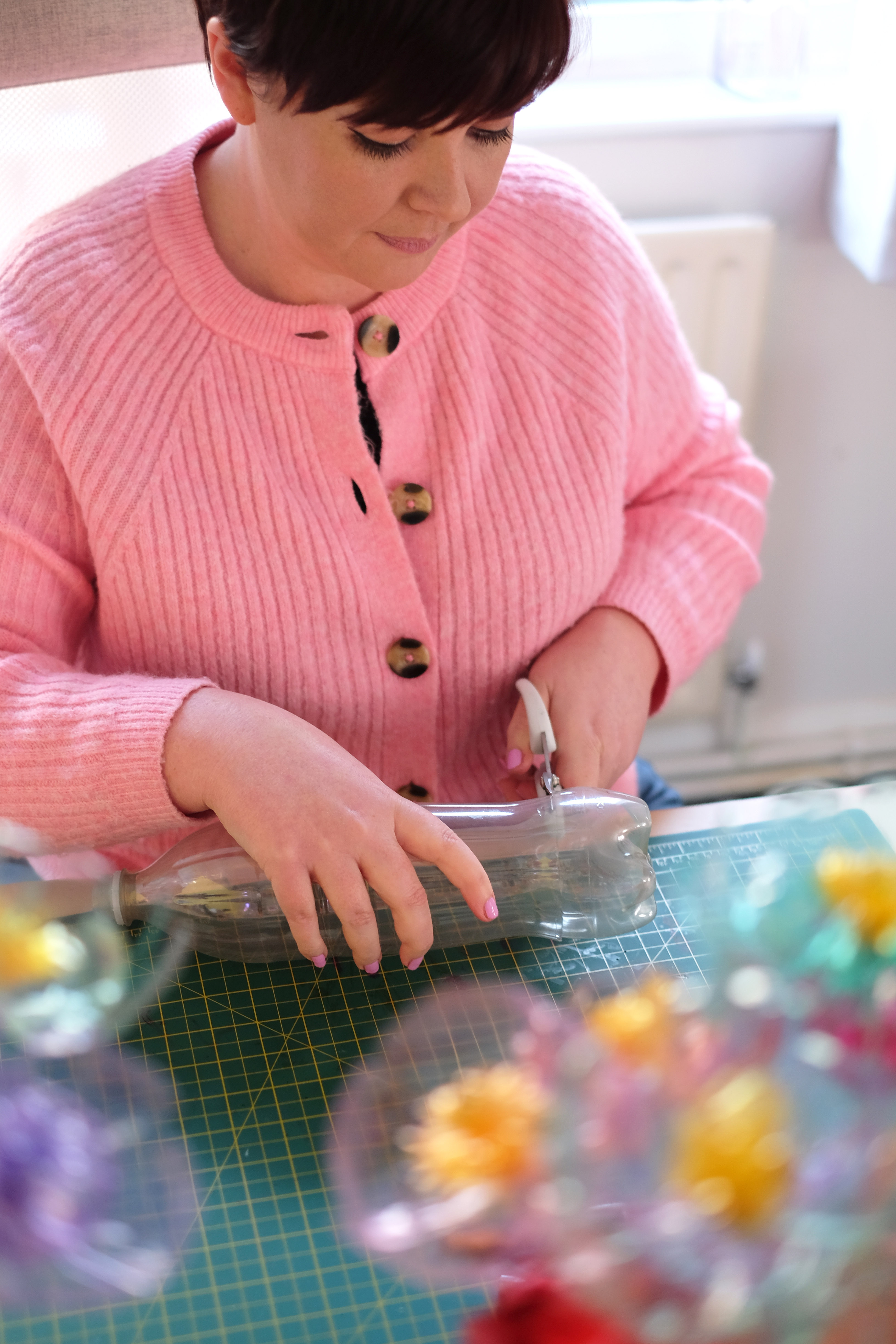 Aimee making plastic bottle flowers, cutting a used plastic bottle by hand