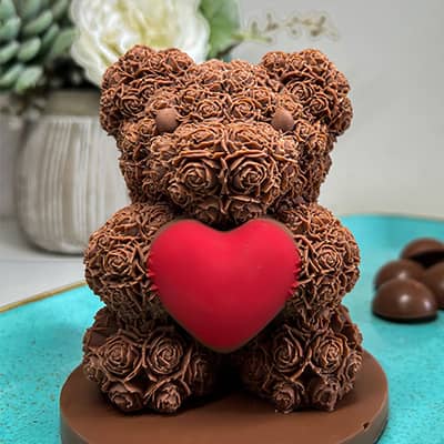 A velvety Belgian milk chocolate bear adorned with delicate roses, symbolizing love. The bear's shell holds chocolate treasures, hazelnut-filled bars.