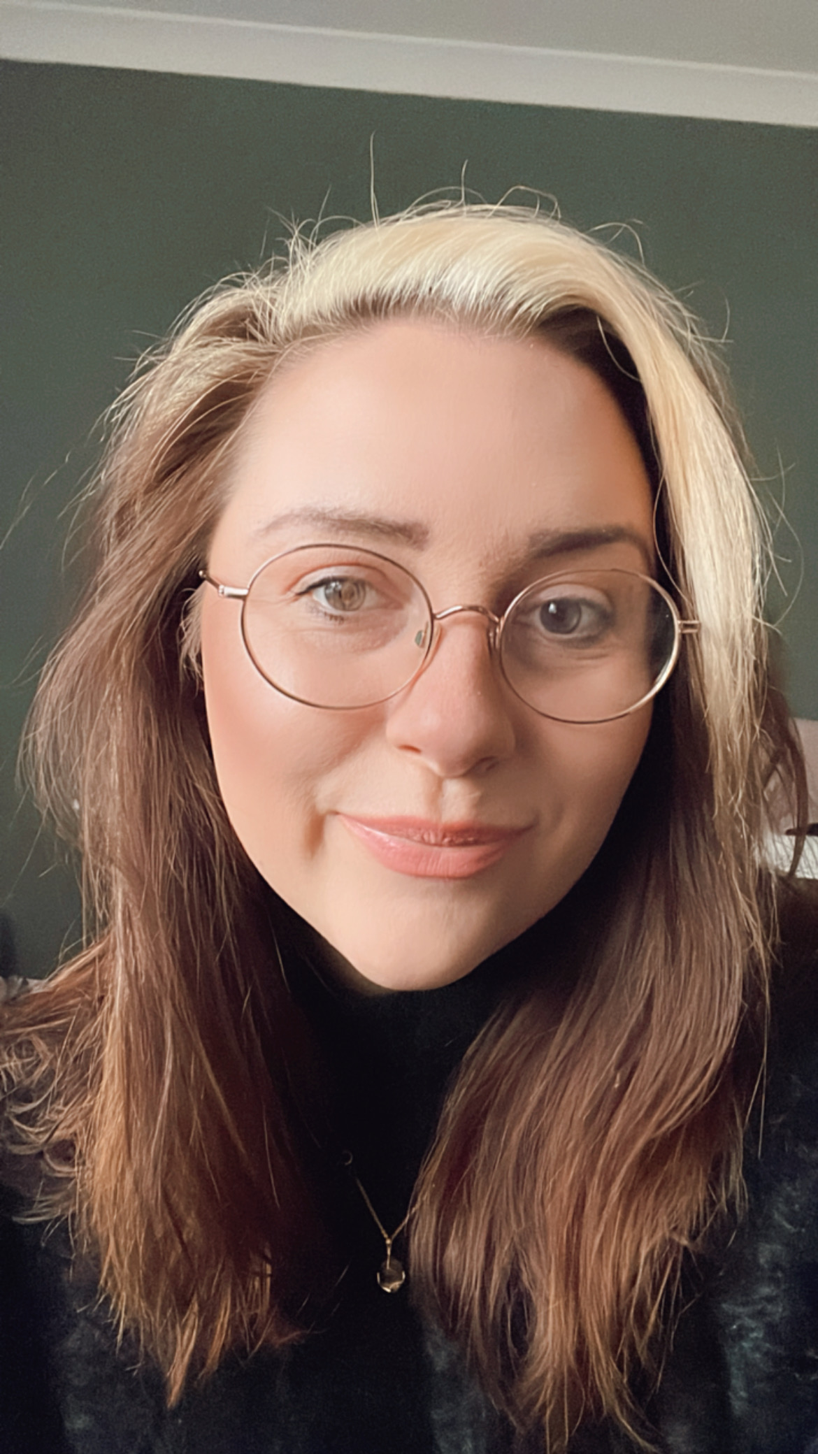 Image of Janine Farley, founder of Omm & Co, brown hair with  blonde at the front, wearing glasses. Green background.