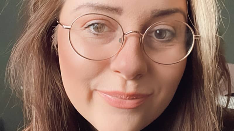 Image of Janine Farley, founder of Omm & Co, brown hair with blonde at the front, wearing glasses. Green background.