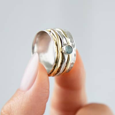 Wide silver spinner ring, featuring three moving bands and a stunning blue topaz stone.