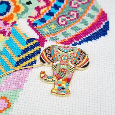 A Mandala Elephant needle minder keeps an embroidery needle in place on a cross stitch design