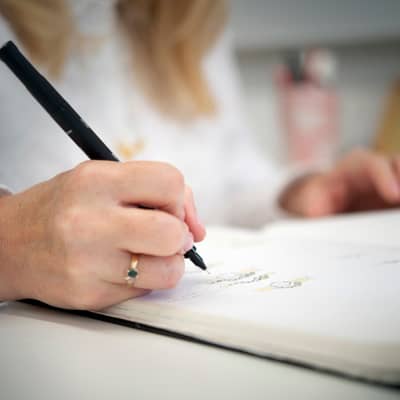 Claire Troughton's hand holding a pen and sketching some jewellery designs