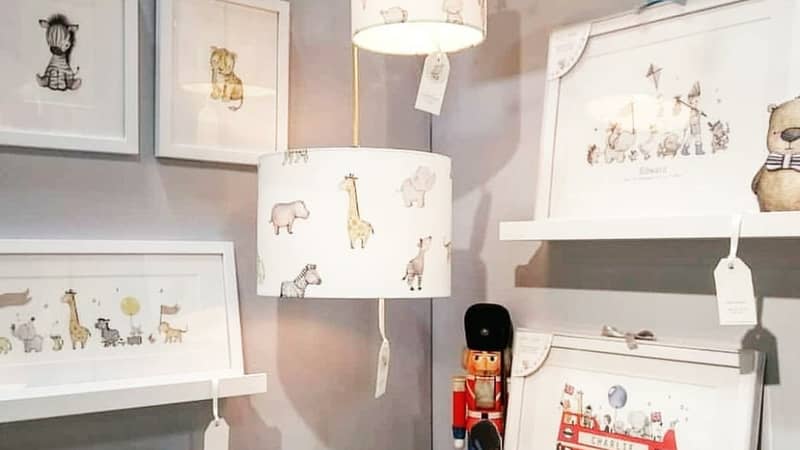 Children's luxury nursery interior designs displayed on a wall including kid's framed wall art prints of a london bus and safari animal lampshades