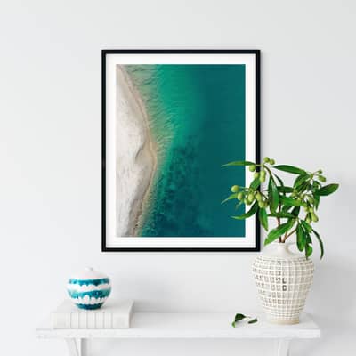 Aerial photography print displayed in a frame on a shelf with a plant